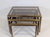 a set of three brass nesting tables with glass tops