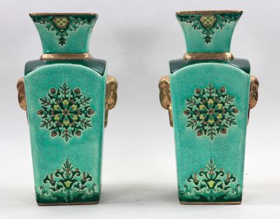 paire de vases verts avec des anses dorées sur fond blanc