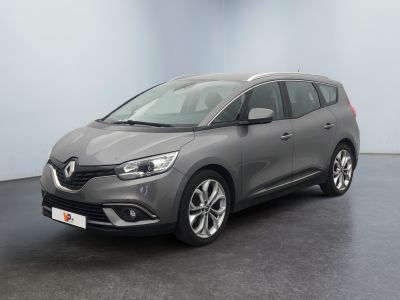 Une voiture grise est garée dans une pièce au sol noir.