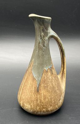 a brown and green vase sitting on a black surface