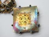 une photo d'un collier orné d'un motif carré