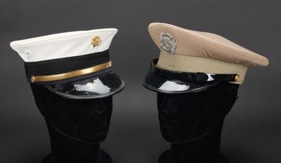 une paire de casquettes militaires posées sur des têtes de mannequins, sur fond noir