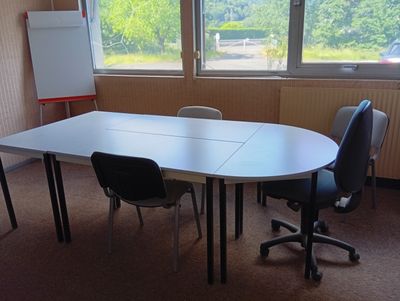 une table avec des chaises et un tableau blanc dans une pièce