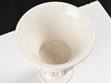 a small white vase sitting on top of a piece of paper
