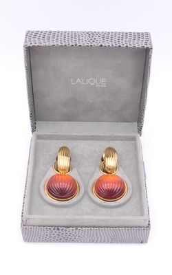 une paire de boucles d'oreilles rouges et dorées dans une boîte