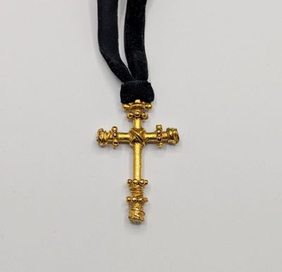 a close up of a cross on a black ribbon on a white surface