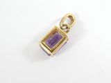 a close up of a purple and gold pendant on a white surface