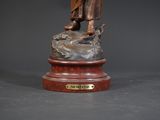 bronze statue of a man with a dog on a wooden base