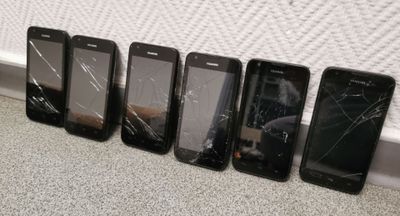 five cell phones are lined up in a row on the floor