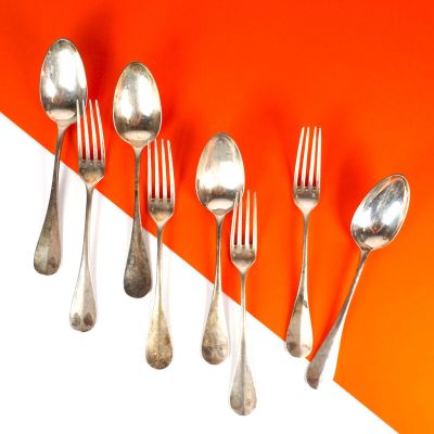 cinq cuillères en argent et deux cuillères en argent sur un fond orange et blanc
