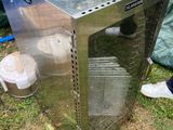 une boîte métallique posée dans l'herbe, à côté d'une poubelle