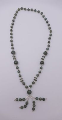 un collier orné d'une croix en perles de verre vertes