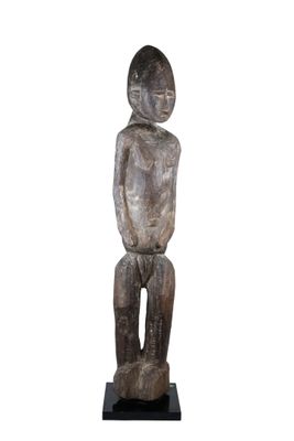 une photo représentant une statue en bois d'une personne assise sur un tabouret