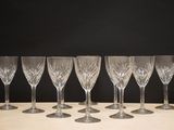 six empty wine glasses lined up on a table against a black background