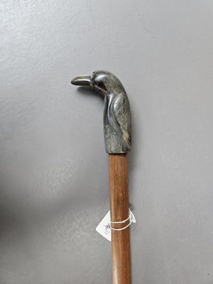 a metal bird on a wooden stick on a gray surface