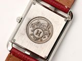 a silver watch with a red strap on a white surface