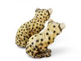two figurines of two cheetah sitting next to each other on a white surface