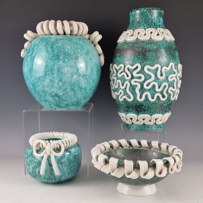 three vases and a bowl are sitting on display on a table