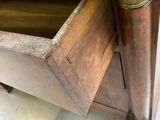 underside view of a wooden chest of drawers with brass handles