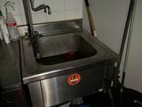 un évier dans un coin de la cuisine, avec un seau contenant des produits d'entretien
