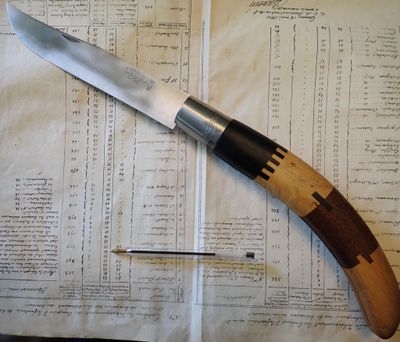 un couteau posé sur un morceau de papier, à côté d'une aiguille