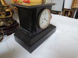 a small clock on a table next to a lamp
