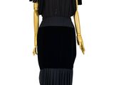 mannequin vêtu d'une robe noire, posé sur un socle en bois, devant un fond blanc