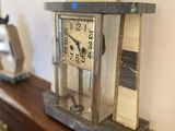 a clock sitting on a shelf with two birds on top of it