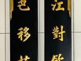 deux panneaux noirs et dorés accrochés au mur d'un immeuble