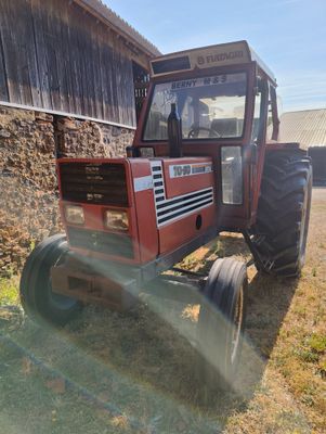 a red tractor parked in front of a barn
