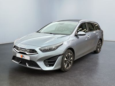 La voiture argentée est garée dans une pièce au sol noir.