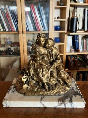 une statue représentant une femme tenant un enfant dans ses bras, posée sur un socle en marbre