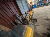 a yellow and black tractor parked in front of a red building