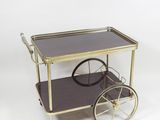 an image of a brass and glass bar cart on wheels