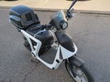 une moto noire et blanche garée sur le bord de la rue