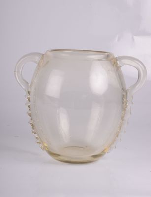 un vase en verre transparent muni de deux anses, posé sur une surface blanche