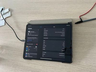 une tablette posée sur une table, à laquelle sont reliés des câbles