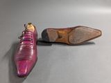 pair of purple leather shoes sitting on top of a gray surface