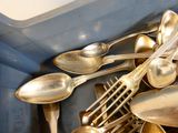 a lot of silver spoons and spoons in a blue container
