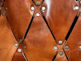 the back of a brown leather chair with rivets and rivets
