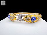 a close up of a gold bracelet with blue and white stones