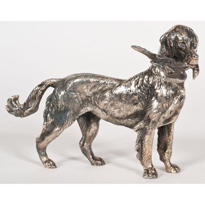 statue en argent représentant un chien tenu en laisse sur fond blanc