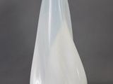 un vase en verre blanc au fond incurvé, posé sur une surface grise