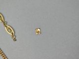 two pieces of gold jewelry are laying on a gray surface