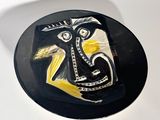 a black plate with a yellow and white painting on it