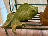 une statue représentant un poisson posée sur une étagère à côté d'un vase