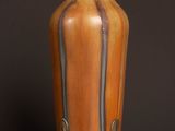 an orange vase sitting on top of a wooden table next to a black wall