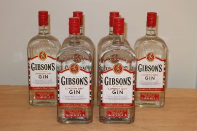 trois bouteilles de gin posées sur une table en bois, avec un mur blanc en arrière-plan