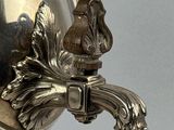 a silver vase that has a bird on it