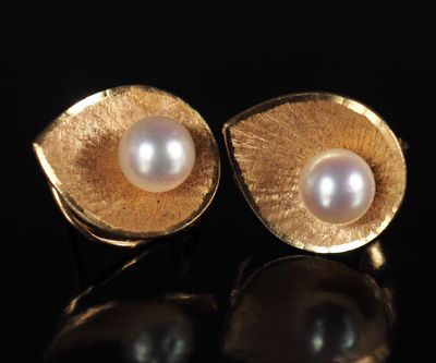 une paire de boucles d'oreilles en or et perles posées sur un fond noir